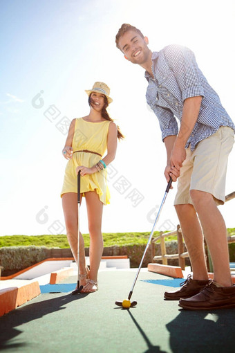 夫妇迷你高尔夫球快乐男人。俱乐部微笑打击球日期有趣的活动自由阳光兴奋年轻的人玩户外推杆推杆蝙蝠夏天幸福草的地盘