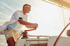 退休奢侈品游艇投资成熟的男人。航行绞车桅杆控制风管理速度人旅游船绳子处理财富假期水位置假期