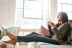 互联网电话女人放松沙发社会媒体发短信浏览首页女孩智能手机在线聊天应用程序在线约会流媒体休息生活房间