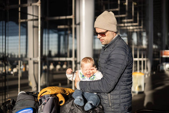 fatherat令人欣慰的哭婴儿婴儿男孩孩子累了坐着前行李车前面机场终端站旅行咻家庭