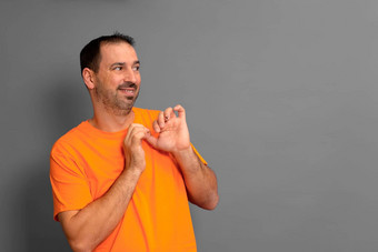 拉美裔男人。胡子穿橙色t恤一边害羞的不好意思表达式孤立的灰色的背景