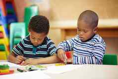 工作创造力学前教育非洲美国男孩集中他们的图纸他们的蜡笔形状