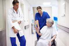 给直女护士推高级病人轮椅走廊会谈医生