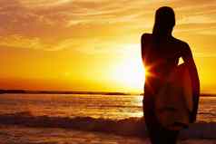 女人携带冲浪板海日落轮廓风景优美的视图女人携带冲浪板海日落轮廓