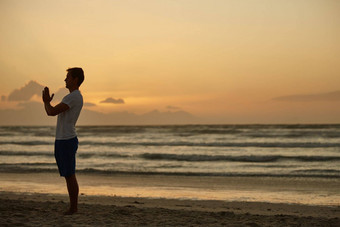 男人。瑜伽海滩日落