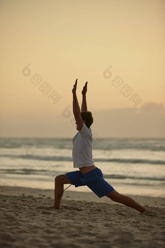 达到健康男人。瑜伽海滩日落