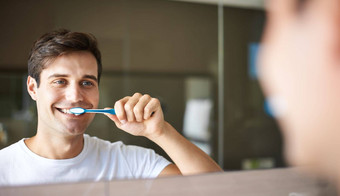保持牙齿清洁健康的特写镜头年轻的男人。刷牙牙齿镜子