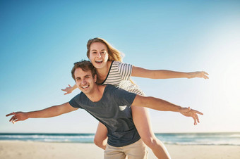 自由生活生活填满爱快乐年轻的夫妇享受肩扛骑海滩