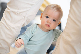 肖像可爱的好奇的<strong>婴</strong>儿<strong>婴</strong>儿男孩孩子采取步骤持有父亲的裤子<strong>首页</strong>可爱的<strong>婴</strong>儿男孩学习走