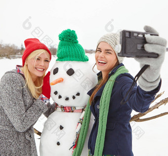 自拍雪人冬天女人朋友采取照片户外雪快乐微笑摄影年轻的女朋友摆姿势图片冷天气