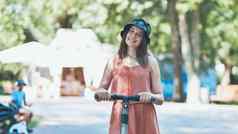 肖像女孩电踏板车摆姿势公园夏天