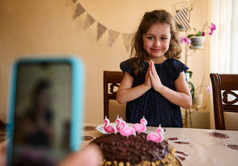 可爱的生日女孩海军衣服持有手掌使吹蜡烛节日蛋糕