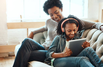 黑色的家庭耳机平板电脑听音乐流媒体在线学习休息室沙发女人妈妈。少年生活房间快乐首页无线网络教育