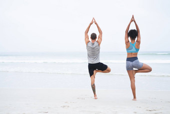 平衡领导实现<strong>后</strong>视镜拍摄年轻的男人。女人练习瑜伽海滩