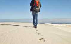 遍历平原后视镜拍摄年轻的女徒步旅行者走沙子沙丘