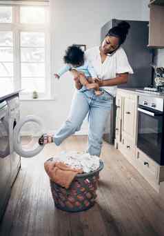 婴儿洗衣等待年轻的妈妈。手机完成做家务持有婴儿首页