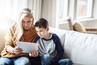 平板电脑爱妈妈。男孩沙发成键质量时间放松周末家庭首页生活方式妈妈孩子数字科技在线游戏社会媒体互联网应用程序