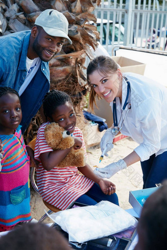 社区健康的快乐志愿者护士给注射社会地位低下的孩子们