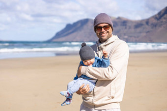 父亲享受纯自然持有玩婴儿婴儿男孩儿子多风的桑迪海滩法马拉兰斯洛特岛西班牙家庭旅行育儿概念