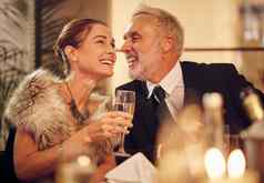 快乐高级夫妇庆祝活动晚餐酒玻璃微笑女人有趣的男人。年聚会，派对成熟的客人微笑笑话优雅的优雅的正式的风格