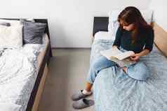 年轻的女人坐着床上宿舍房间阅读书类
