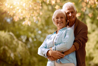 自然拥抱肖像高级夫妇模型拥抱户外公园退休快乐浪漫爱成熟的男人。女人拥抱花园植物树