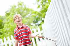 想象力界限可爱的年轻的男孩运行坚持白色哨栅栏后院