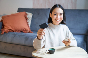 微笑可爱的亚洲女人信贷卡智能<strong>手机支付</strong>账单在线持有移动电话相机