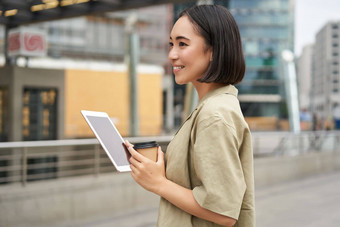 现代人年轻的亚洲女人平板电脑饮料咖啡街应用程序微笑