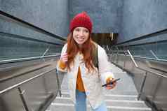 肖像红色头发的人女孩旅游楼梯智能手机路线移动电话应用程序持有背包微笑