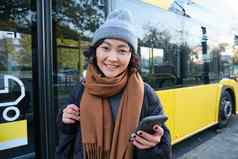图像女孩学生等待公共运输检查时间表智能手机应用程序站城市公共汽车