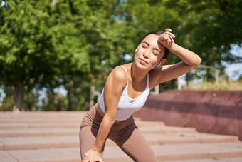 肖像女运动员气喘吁吁采取打破慢跑培训出汗运行在户外