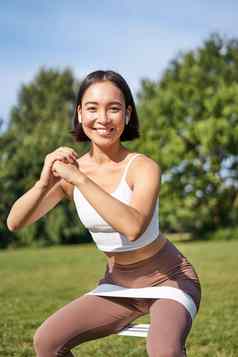 亚洲健身女孩下蹲公园电阻乐队伸展运动瑜伽绳子锻炼培训新鲜的空气