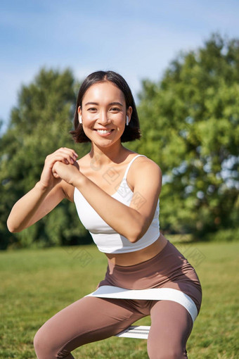 亚洲健身女孩<strong>下蹲</strong>公园电阻乐队伸展运动瑜伽绳子锻炼培训新鲜的空气