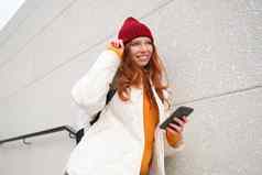 时尚的红色头发的人女人红色的他倾斜墙街持有智能手机互联网电话应用程序读取消息
