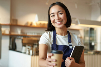 微笑友好的女服务员咖啡商店咖啡师给外卖订单卡布奇诺咖啡纸杯外卖站咖啡馆