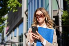 肖像自信女商人站街办公室建筑移动电话订单出租车智能手机应用程序阅读消息