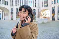 细胞技术年轻的朝鲜文女人会谈移动电话使电话调用首页走街城市中心电话谈话