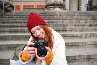 肖像年轻的摄影师女孩坐在楼梯专业相机需要照片在户外使生活方式拍摄