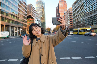 快乐亚洲女孩旅游需要自拍城市中<strong>心</strong>使<strong>视频</strong>调用波智能手机相机问候电话