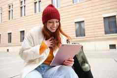 美丽的红色头发的人女人红色的他坐在背包热水瓶数字平板电脑在户外连接无线网络文本消息书票在线
