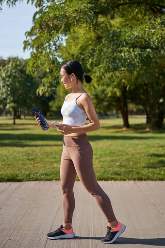 活跃的亚洲女孩健身服装锻炼公园<strong>走运</strong>动服装智能手机水瓶