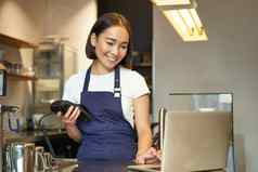 微笑亚洲女孩咖啡师工作咖啡馆服务客户端移动PC卡读者收到钱订单销售咖啡