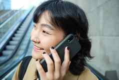 头像微笑朝鲜文女人智能手机使电话调用自动扶梯城市通勤大学