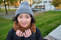 肖像可爱的亚洲女孩他围巾走小镇寒冷的春天天气微笑快乐坐在公园绿色草