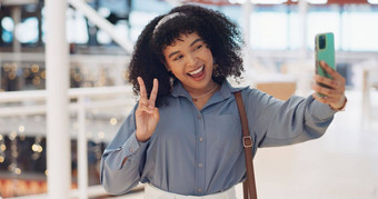 黑色的女人影响者自拍和平标志微笑智能手机走城市购物购物中心快乐电话女人手手势社会媒体网络在线应用程序购物中心亚特兰大