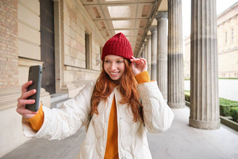 时尚的红色头发的人女孩旅游需要自拍前面旅游吸引力使照片智能手机移动相机提出了