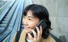 头像微笑朝鲜文女人智能手机使电话调用自动扶梯城市通勤大学