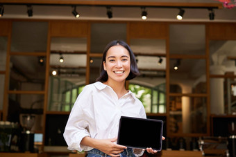 微笑亚洲女经理咖啡馆老板显示平板电脑屏幕展示smth设备