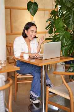 兴奋亚洲女孩发现在线移动PC屏幕惊讶惊讶脸坐着咖啡馆